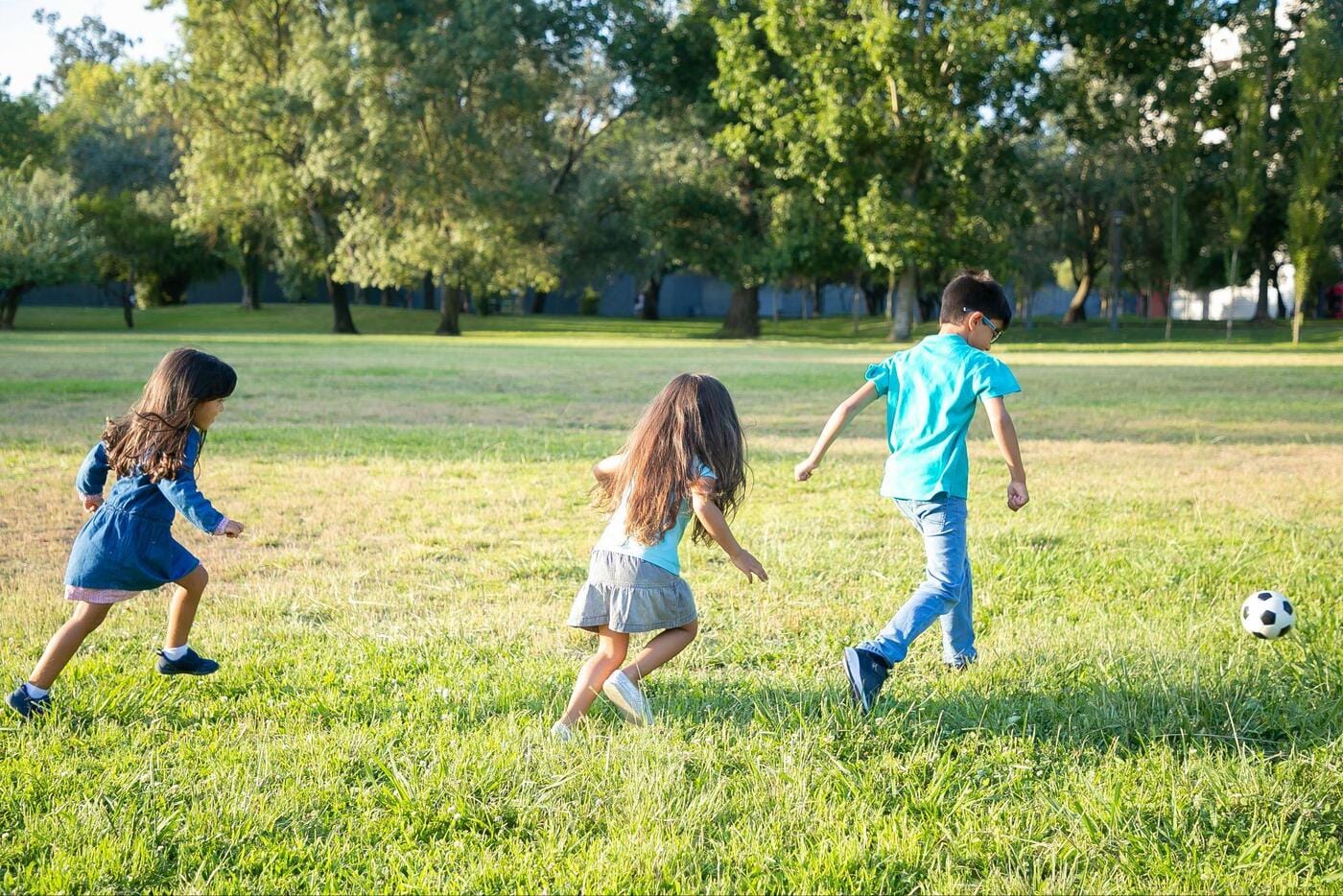 Deti hrajúce futbal na trávniku v parku